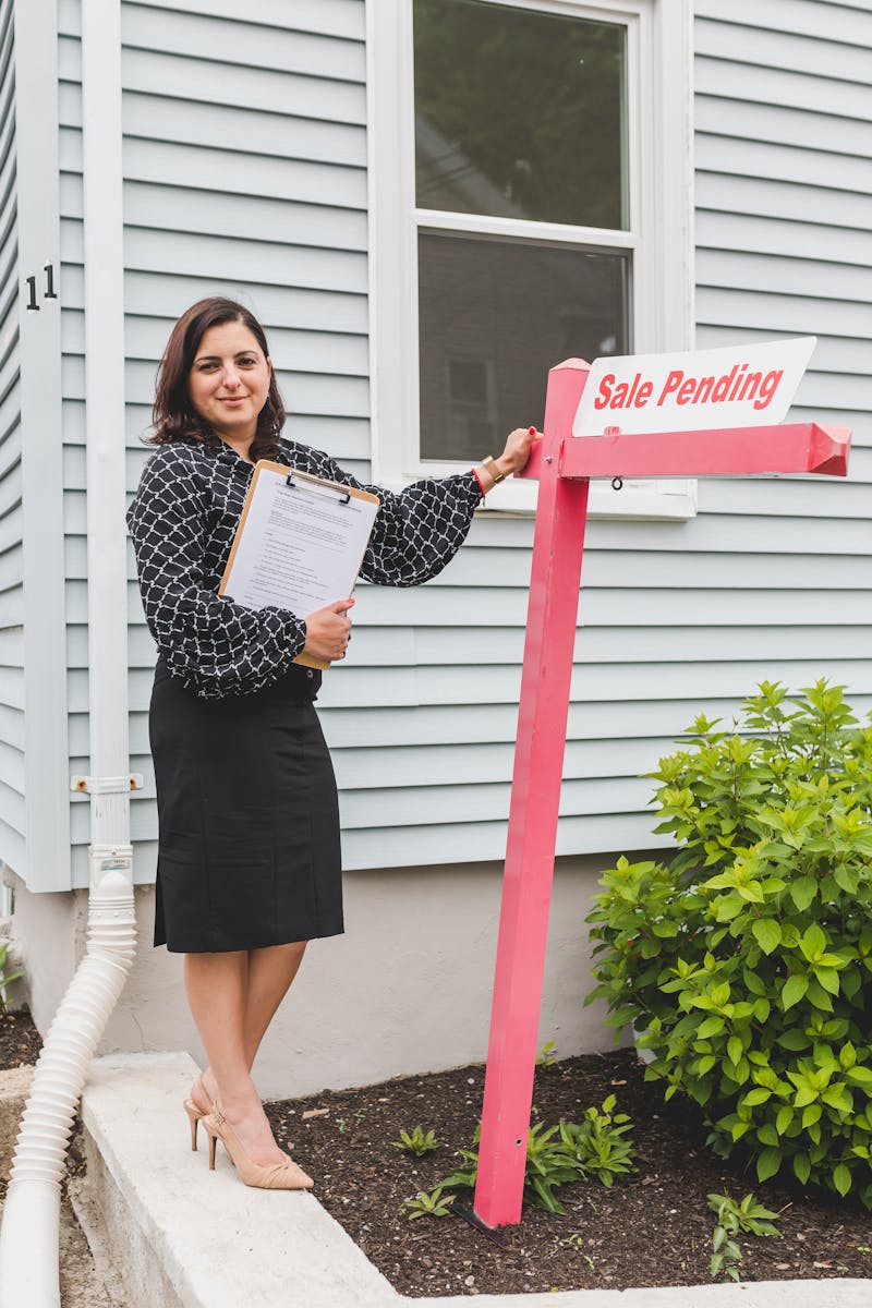 Woman standing beside For Sale sign